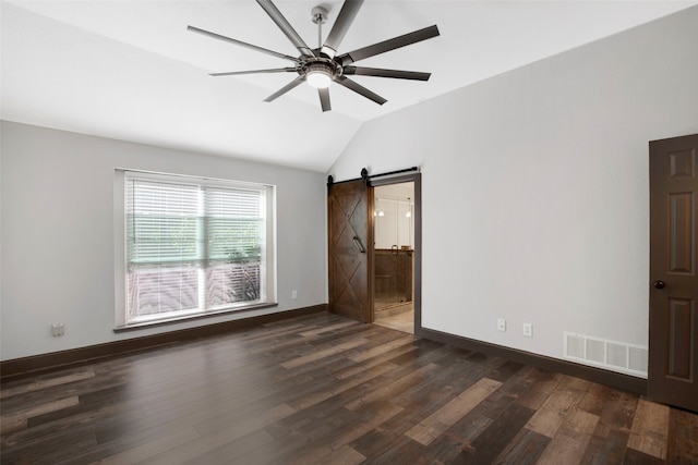 empty room featuring a barn door, ceiling fan, dark hardwood / wood-style flooring, and vaulted ceiling