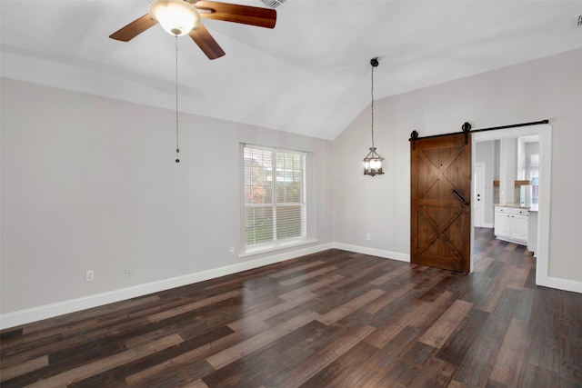 spare room featuring ceiling fan, a barn door, lofted ceiling, and dark wood-type flooring