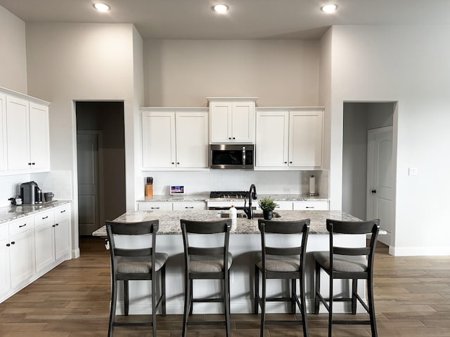 kitchen with an island with sink and white cabinets