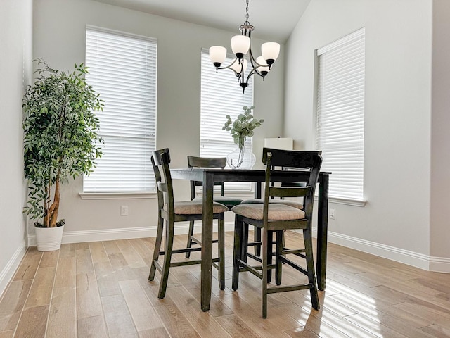 dining room with lofted ceiling, a chandelier, and light hardwood / wood-style floors