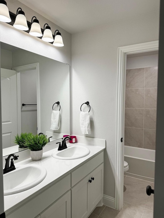 full bathroom featuring tile patterned flooring, vanity, tiled shower / bath, and toilet