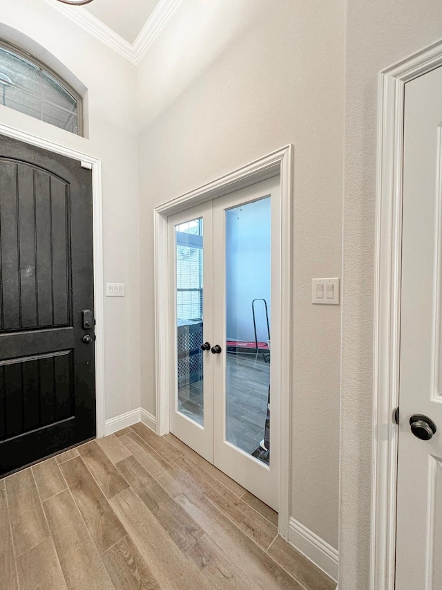 foyer entrance with french doors, ornamental molding, and light hardwood / wood-style flooring