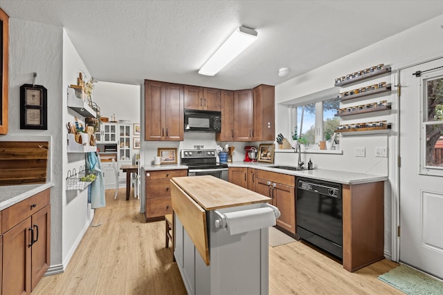 kitchen with sink, black appliances, a textured ceiling, and light hardwood / wood-style floors