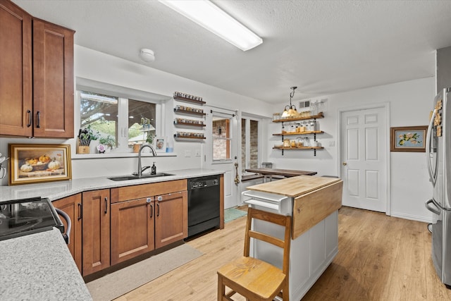 kitchen featuring sink, stainless steel appliances, decorative light fixtures, and light wood-type flooring