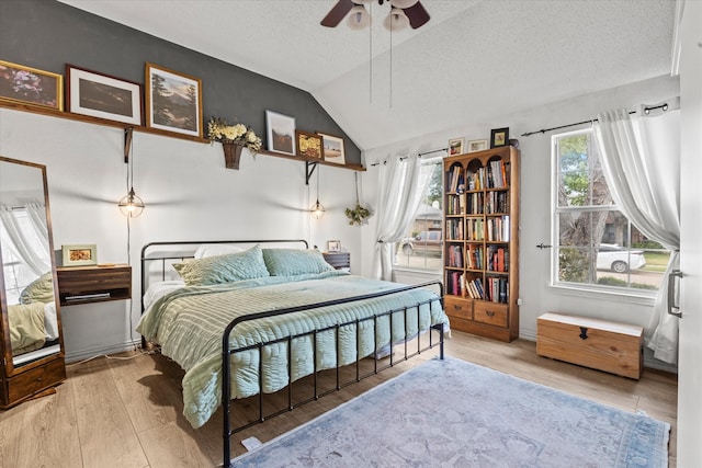 bedroom featuring a textured ceiling, ceiling fan, lofted ceiling, and light wood-type flooring