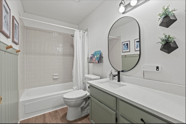 full bathroom with vanity, hardwood / wood-style flooring, toilet, shower / bath combo with shower curtain, and a textured ceiling