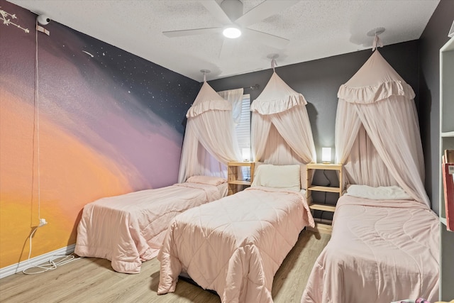 bedroom featuring ceiling fan, wood-type flooring, and a textured ceiling