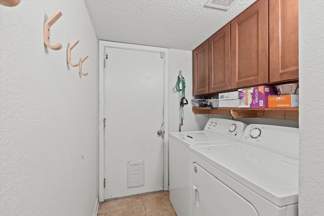 laundry area featuring cabinets, a textured ceiling, separate washer and dryer, and light tile patterned flooring