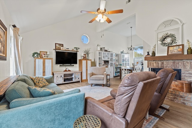 living room featuring french doors, ceiling fan with notable chandelier, high vaulted ceiling, light hardwood / wood-style flooring, and a fireplace