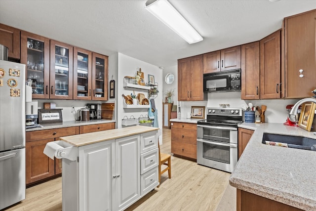 kitchen featuring sink, light hardwood / wood-style flooring, a textured ceiling, a kitchen island, and stainless steel appliances