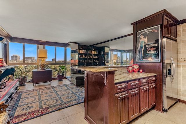 kitchen with kitchen peninsula, light stone countertops, a breakfast bar, and light tile patterned floors