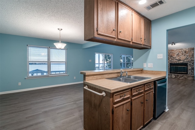 kitchen with kitchen peninsula, dark hardwood / wood-style flooring, decorative light fixtures, and sink