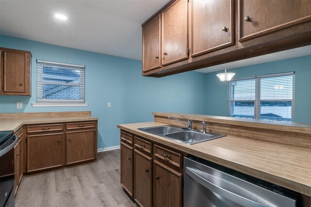 kitchen with pendant lighting, dishwasher, sink, electric range, and light hardwood / wood-style floors