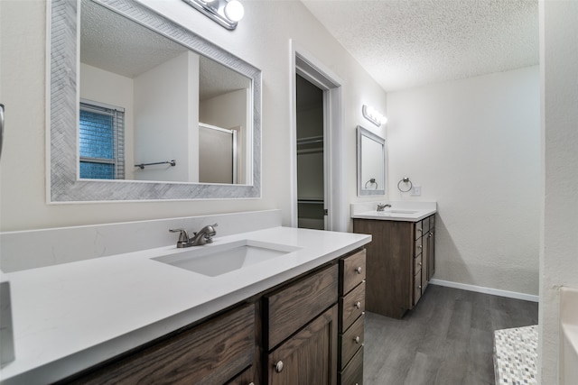 bathroom with vanity, a textured ceiling, hardwood / wood-style flooring, and a shower with door