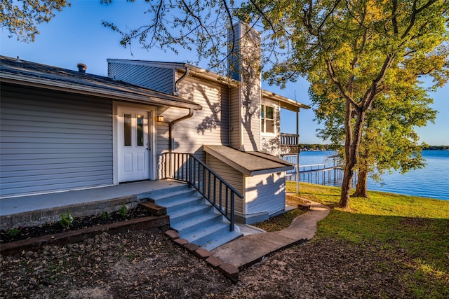 view of exterior entry with a lawn and a water view