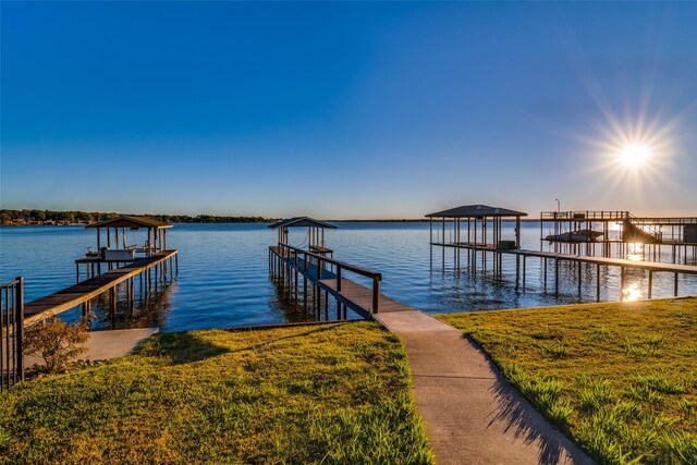 view of dock with a yard and a water view