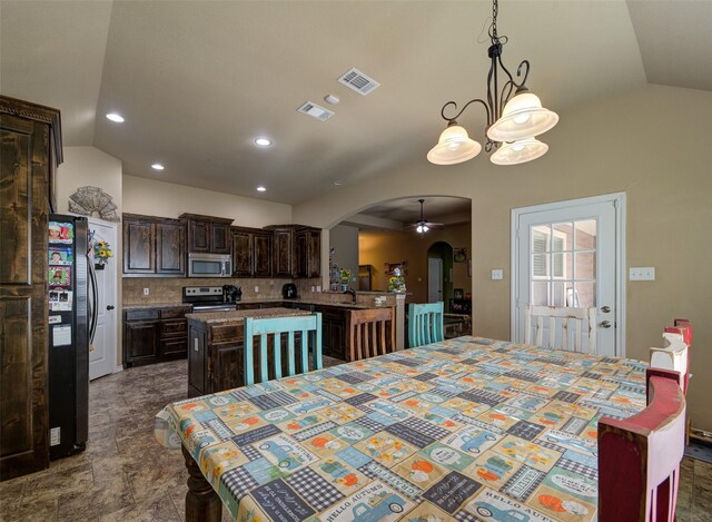 dining room with ceiling fan with notable chandelier, lofted ceiling, and sink