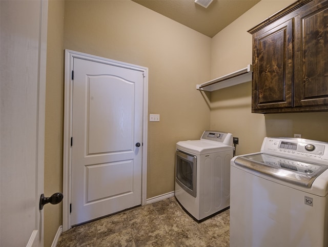 clothes washing area with washing machine and dryer, cabinets, and a textured ceiling