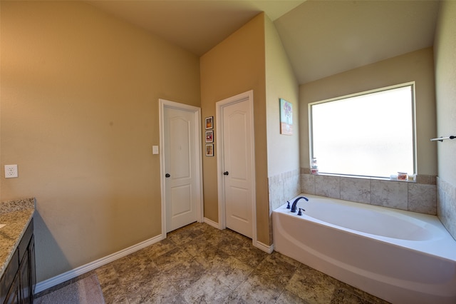 bathroom featuring a washtub, vanity, and vaulted ceiling