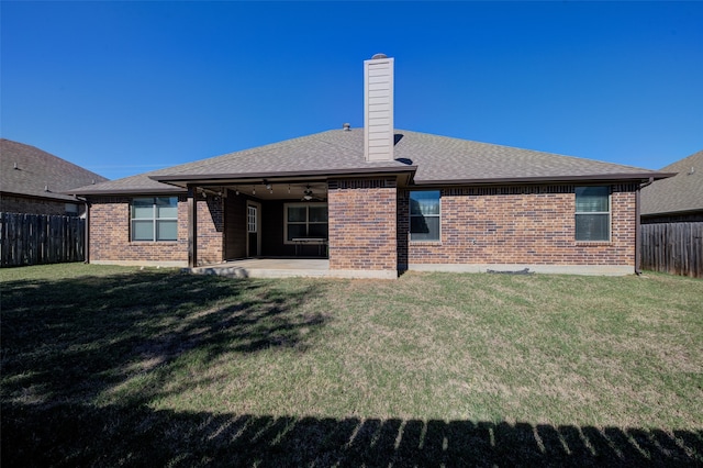 rear view of property with ceiling fan, a patio area, and a lawn