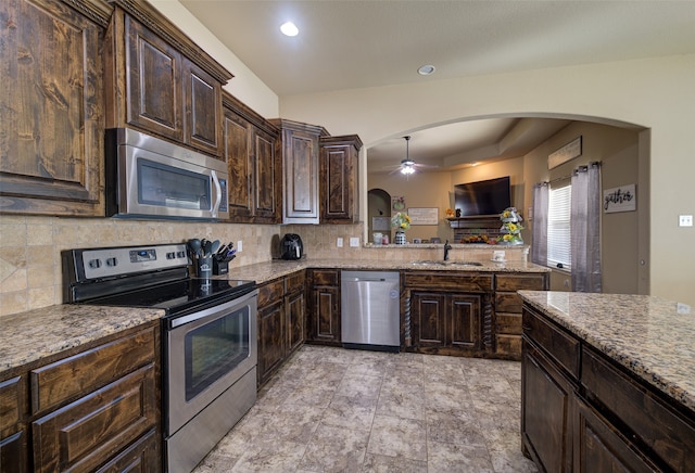 kitchen with dark brown cabinetry, stainless steel appliances, backsplash, and sink