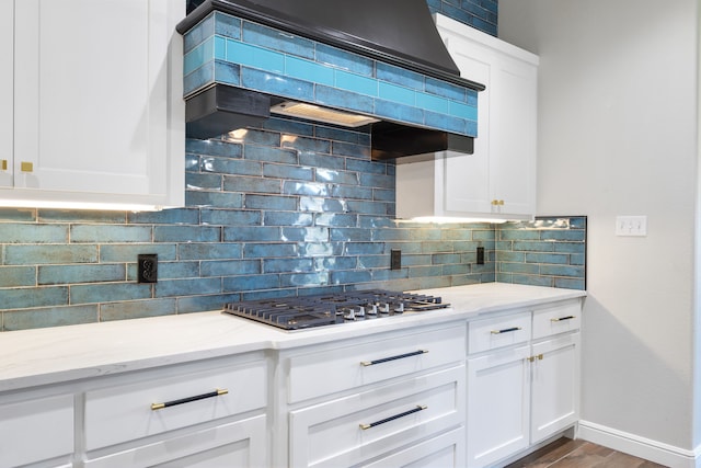 kitchen with premium range hood, decorative backsplash, white cabinets, and stainless steel gas cooktop