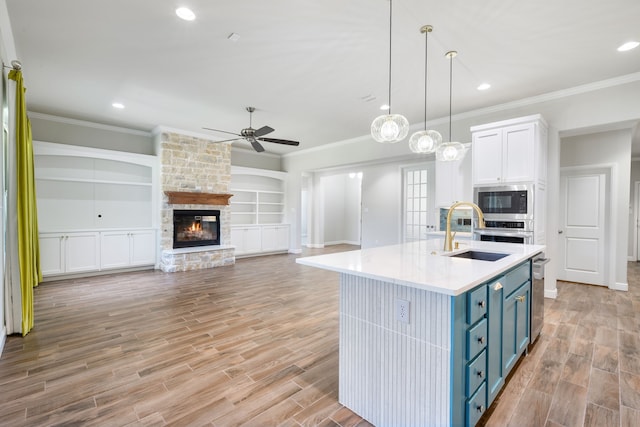 kitchen with blue cabinets, built in shelves, ceiling fan, a fireplace, and white cabinetry