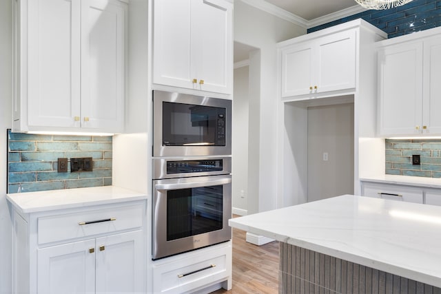 kitchen featuring oven, crown molding, light stone countertops, tasteful backsplash, and white cabinetry