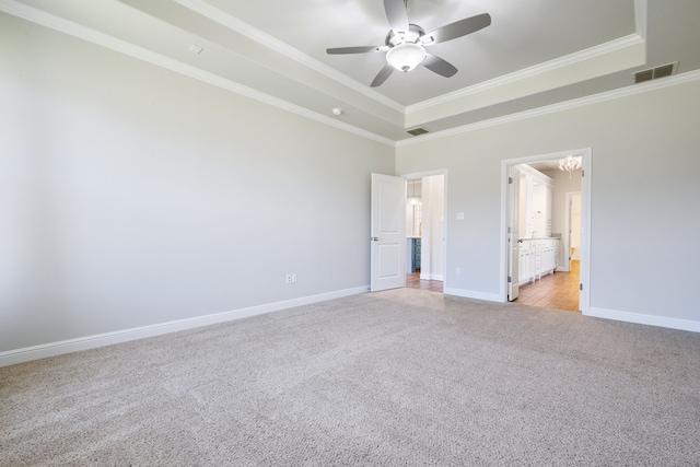 unfurnished bedroom featuring a tray ceiling, ensuite bath, ceiling fan, and ornamental molding