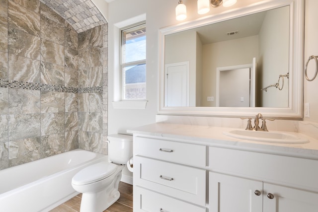 full bathroom featuring tiled shower / bath, vanity, and toilet