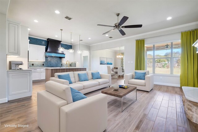 living room featuring hardwood / wood-style floors, a tile fireplace, ceiling fan, built in shelves, and ornamental molding