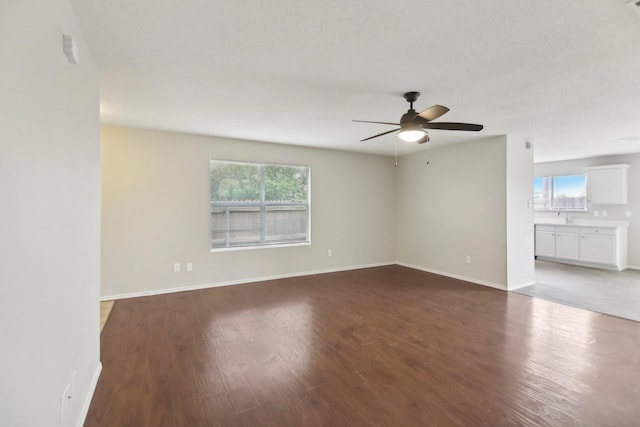 empty room featuring ceiling fan, dark hardwood / wood-style flooring, a textured ceiling, and sink