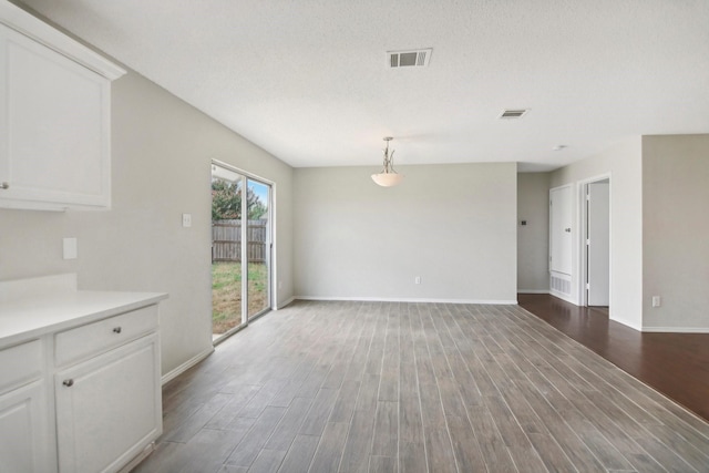 unfurnished dining area featuring a textured ceiling and hardwood / wood-style flooring