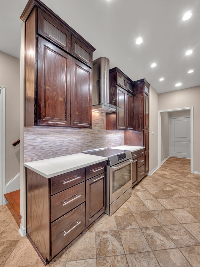 kitchen with dark brown cabinetry, stainless steel stove, tasteful backsplash, and wall chimney range hood