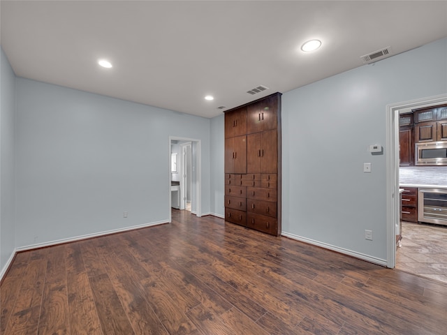 empty room with dark wood-type flooring and beverage cooler