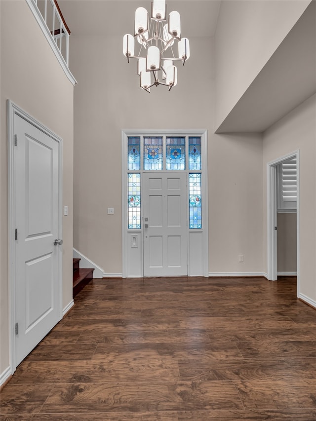 entryway with a notable chandelier, a towering ceiling, and dark wood-type flooring