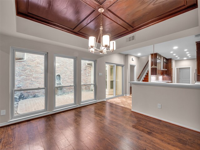 spare room with a chandelier, a wealth of natural light, light hardwood / wood-style floors, and wooden ceiling