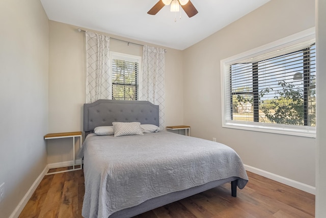 bedroom with multiple windows, ceiling fan, and hardwood / wood-style flooring