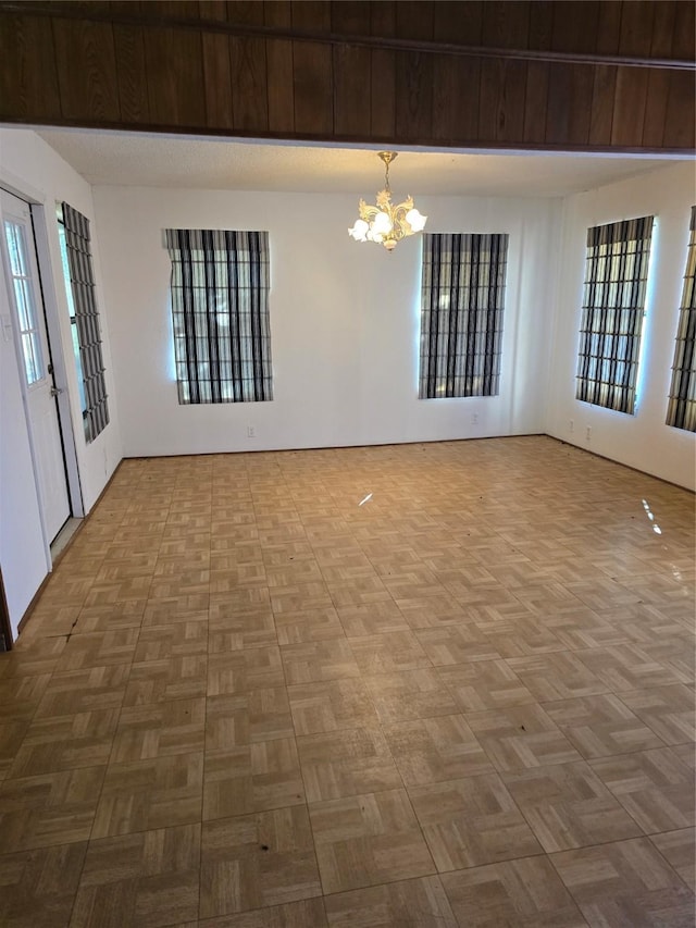 spare room featuring parquet floors, a chandelier, and basketball hoop