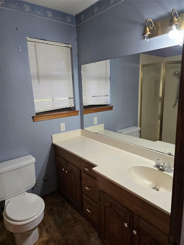 bathroom featuring a textured ceiling, an enclosed shower, vanity, and toilet