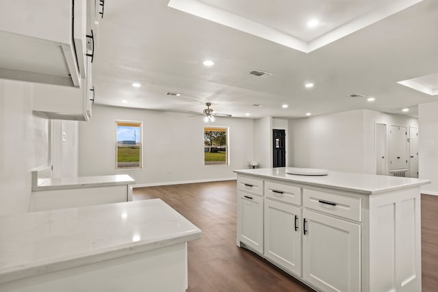 kitchen featuring white cabinets, dark hardwood / wood-style floors, a center island, and ceiling fan