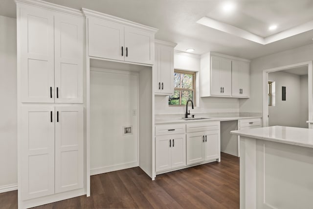 kitchen featuring white cabinets, dark hardwood / wood-style floors, a raised ceiling, and sink