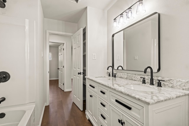 bathroom with hardwood / wood-style floors, vanity, and washtub / shower combination