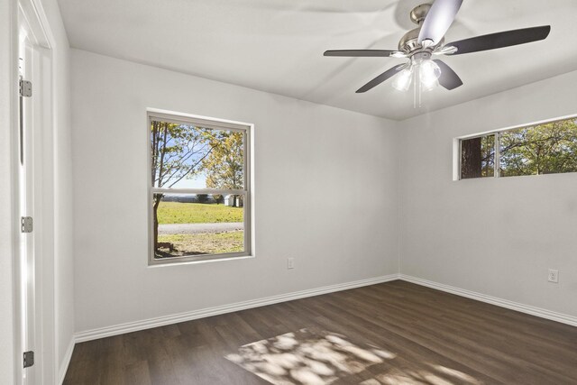 empty room with ceiling fan, dark wood-type flooring, and a wealth of natural light