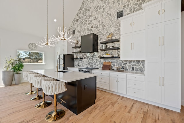 kitchen with stainless steel appliances, high vaulted ceiling, pendant lighting, a center island with sink, and white cabinets