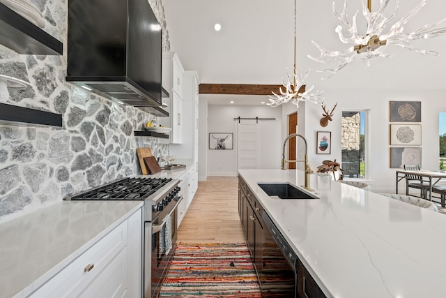 kitchen featuring a barn door, white cabinetry, high end stainless steel range oven, and sink