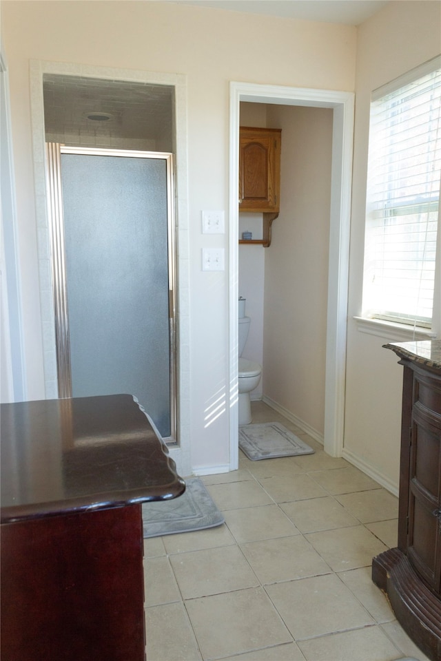 bathroom with tile patterned floors, toilet, vanity, and walk in shower