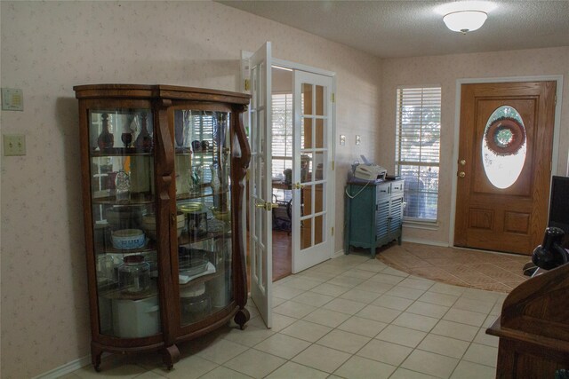 entryway with french doors, light tile patterned floors, and a textured ceiling