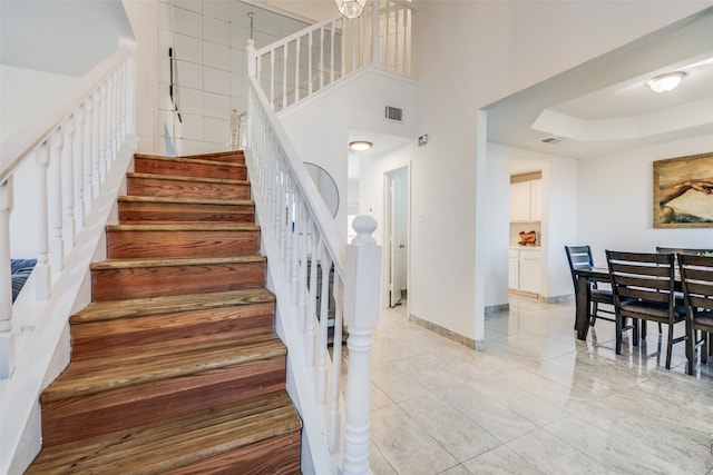 stairway featuring a towering ceiling and a tray ceiling