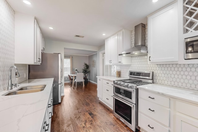 kitchen featuring sink, dark wood-type flooring, wall chimney range hood, white cabinets, and appliances with stainless steel finishes